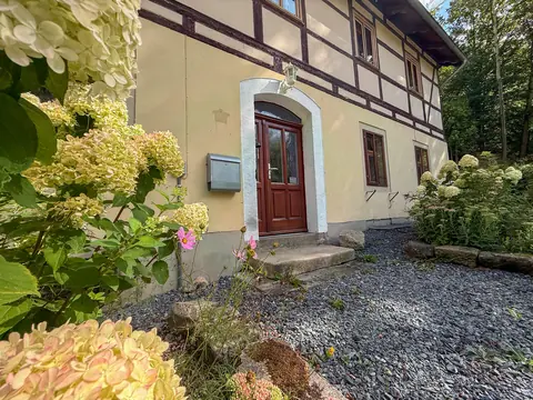 Eingang des Hauptgebäudes mit Sandsteingewände und Hortensien