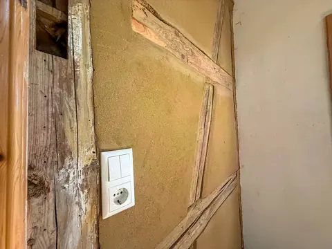 Detail einer Lehmwand mit sichtbarem Fachwerkbalken